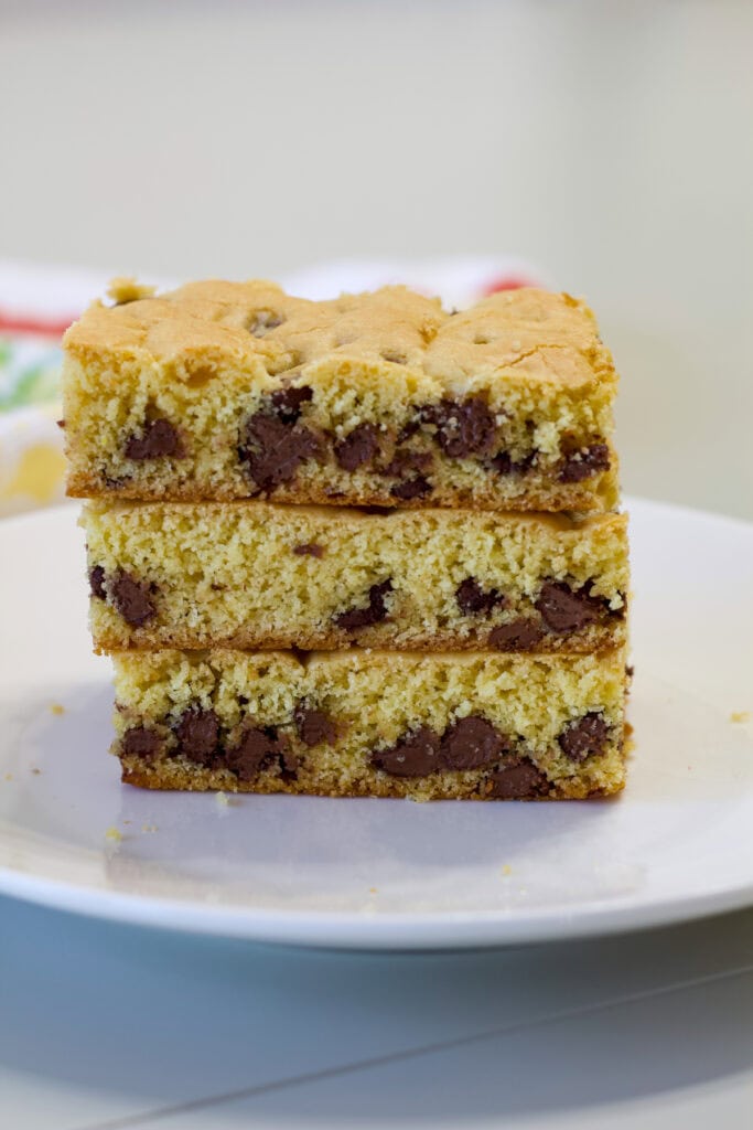 Three yellow cake mix chocolate chip cookie bars stacked on a white plate.