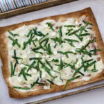 The entire uncut baked lavash flatbread pizza on a rimmed baking sheet.