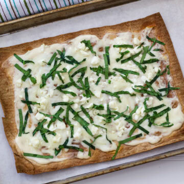 The entire uncut baked lavash flatbread pizza on a rimmed baking sheet.