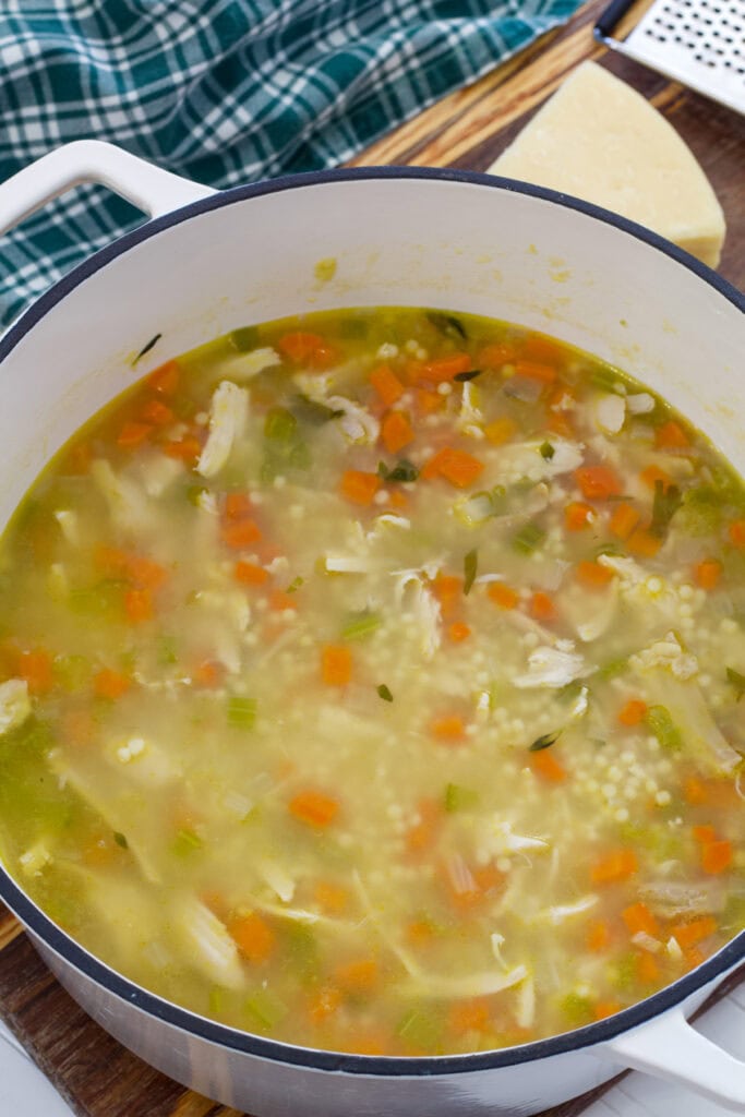 A large white ceramic soup pot with the entire batch of chicken pastina soup.