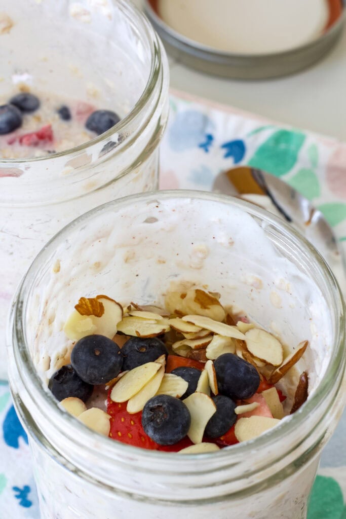 Overhead shot of the oats in the mason jar after they've been topped with a few fresh berries and slivered almonds.