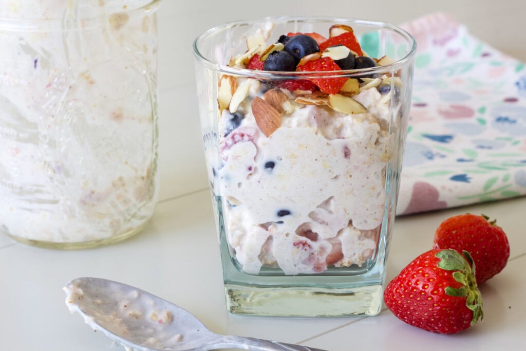 The glass of overnight oats sitting next to the jar they were stored in the refrigerator in.