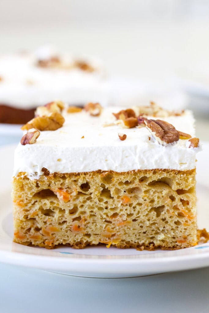 Close up side shot of one piece of carrot cake so the inside crumb and layer of frosting are visible.