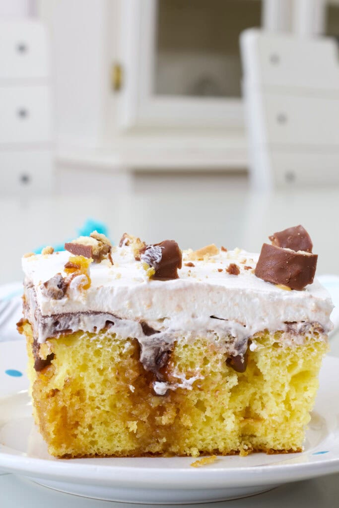 One piece of Twix Poke Cake so the caramel sauce and pudding inside is visible.