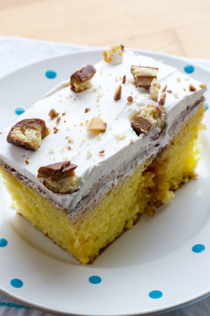One piece of cake on a white plate that has blue polka dots on it.