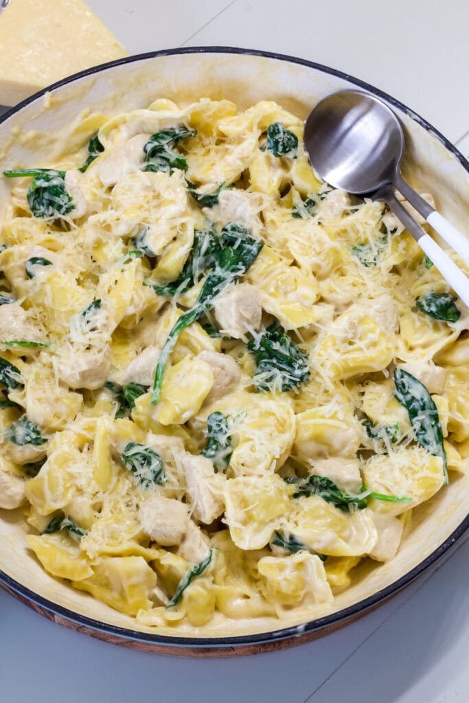 A pan full of Chicken and Tortellini Alfredo topped with grated parmesan cheese.