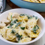 Feature image of one serving of tortellini alfredo in a white bowl.