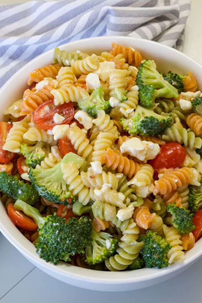 Close up of the entire batch of rainbow pasta salad in a white serving bowl.