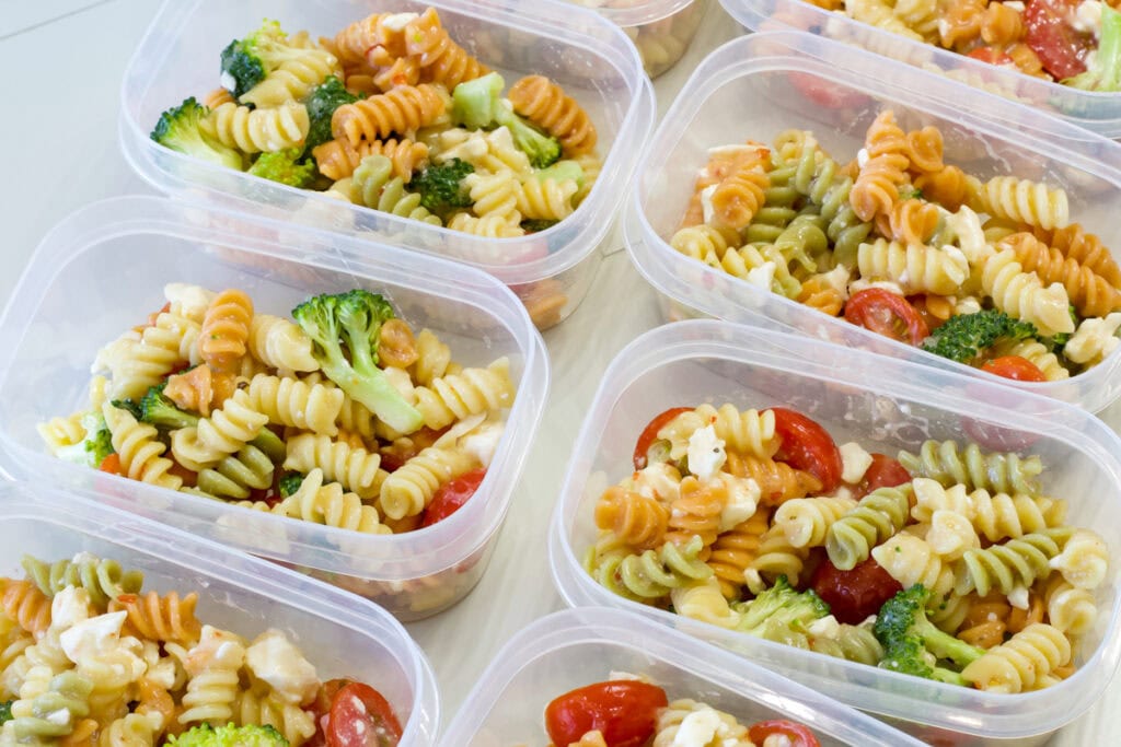 Several plastic bowl with a serving of rainbow pasta salad that I've made for meal prep lunches for the week.