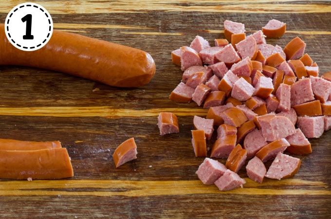 The smoked sausage on a wooden cutting board, some has been cut and some hasn't.