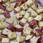 Feature image of the Herb Roasted Red Potatoes on a parchment line rimmed baking sheet.