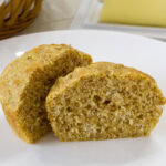 Feature image of the cut in half muffin on a white plate.