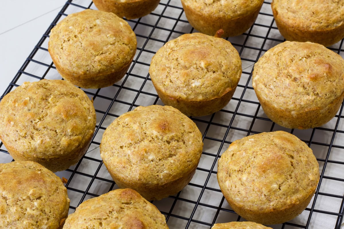 The dozen Savory Cornbread Muffins with Oatmeal cooling on a black wire rack,