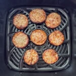 Eight sausage patties in the air fryer basket after being cooked.