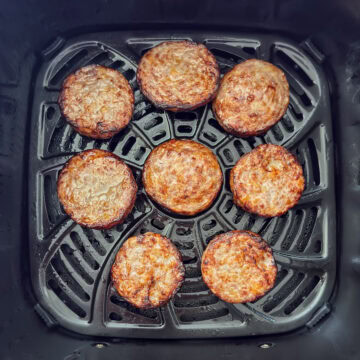Eight sausage patties in the air fryer basket after being cooked.