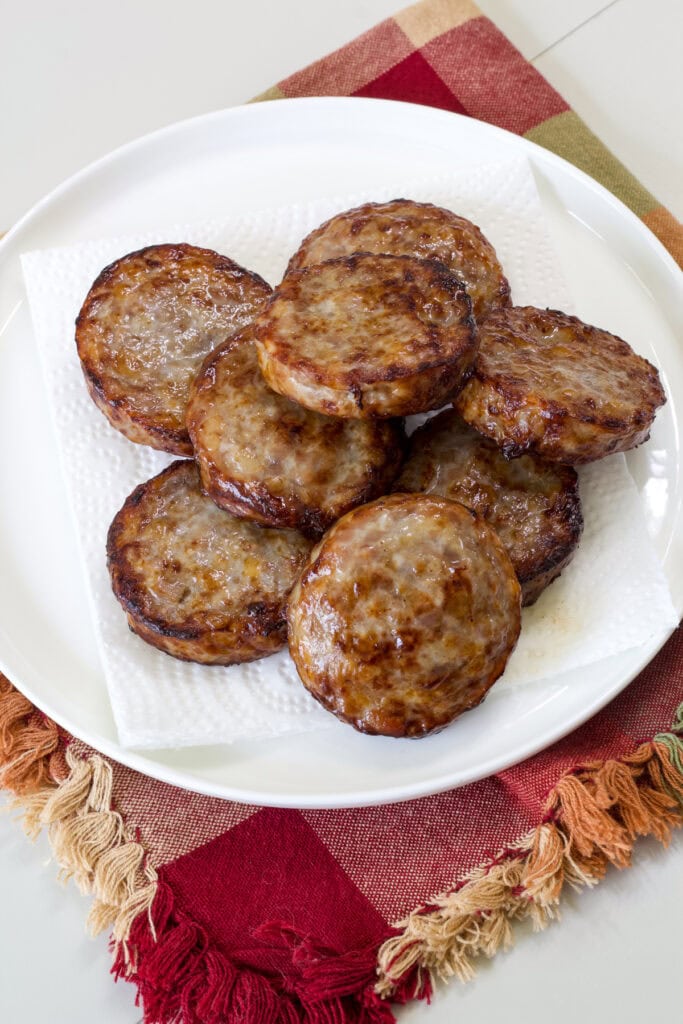 Eight Air Fryer Sausage Patties on a serving plate lined with a paper towel.