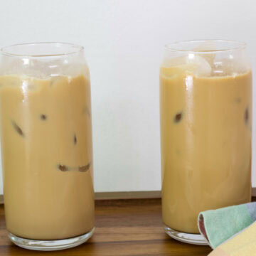 Feature image of two glasses of Dunkin French Vanilla Swirl Iced Coffee on a wooden tray.
