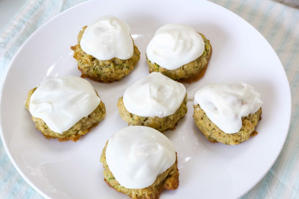 Sic Zucchini Cookies with Frosting on a white plate that's on a striped napkin.