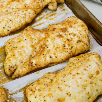 Feature image of baked chicken breasts on the rimmed baking sheet after coning out of the oven.
