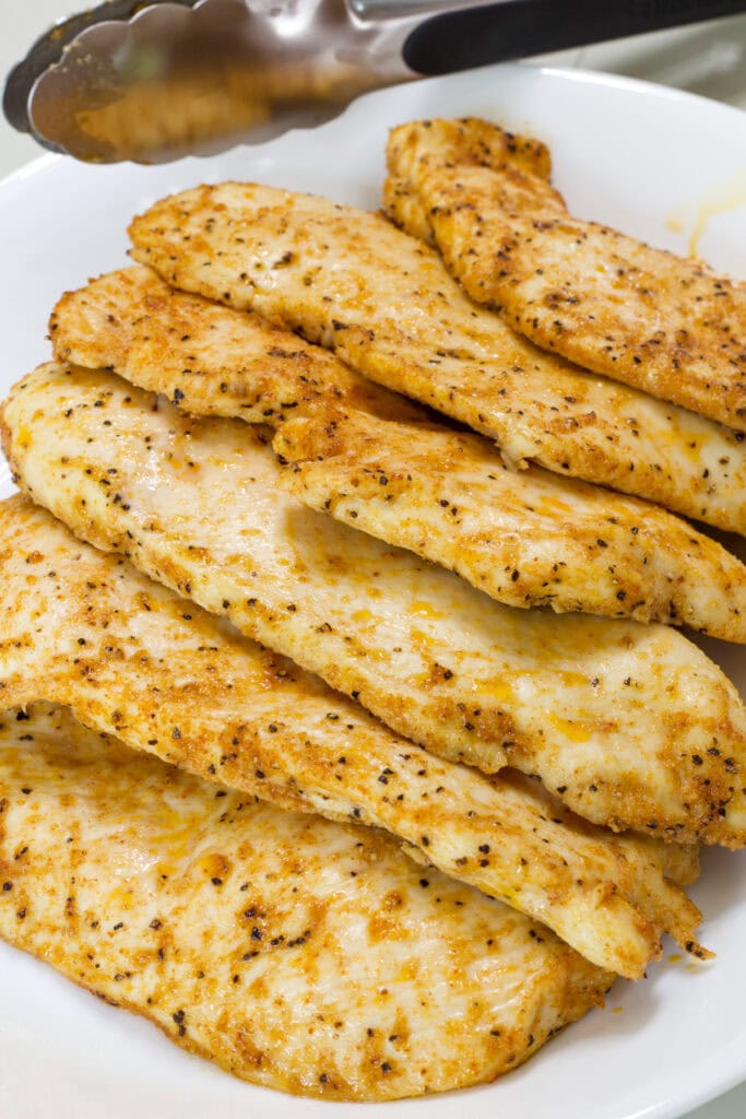 Six Baked Thin Chicken Breasts on a white serving platter.