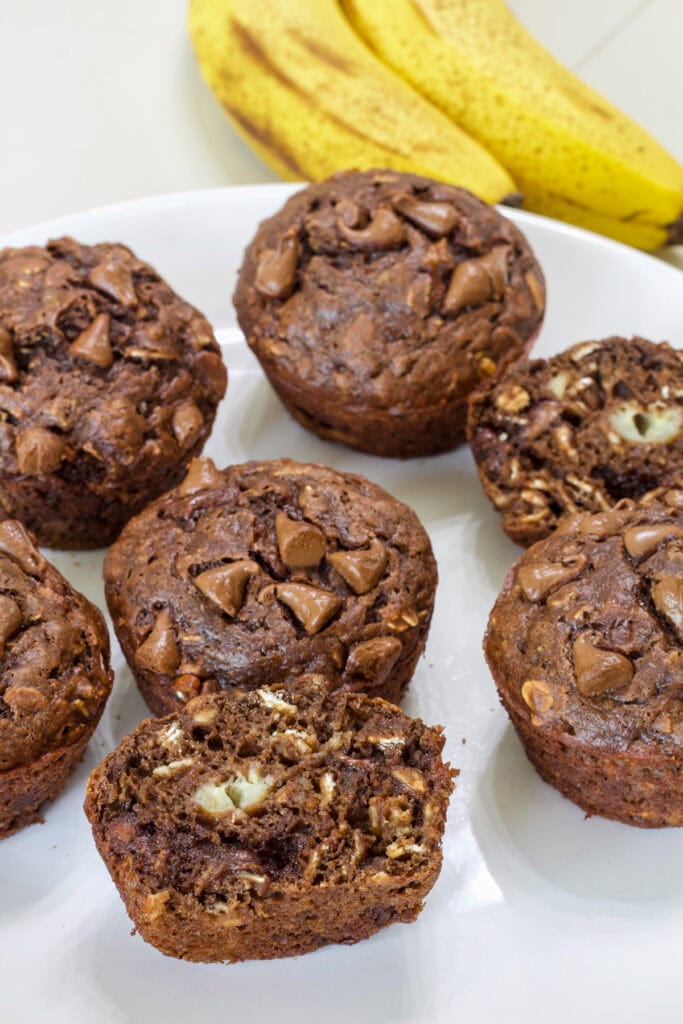 Several muffins on a plate, one is split open so the inside is visible.