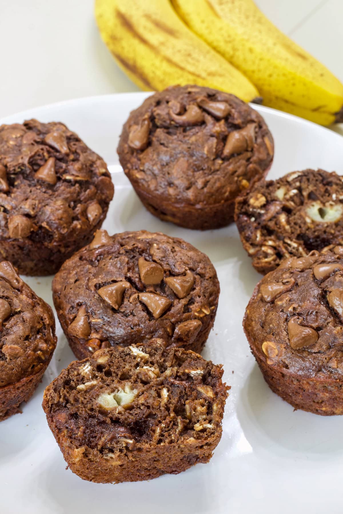 Several muffins on a plate, one is split open so the inside is visible.
