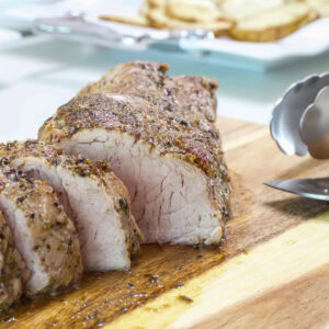 Feature image of the roasted pork tenderloin on a wooden cutting board.
