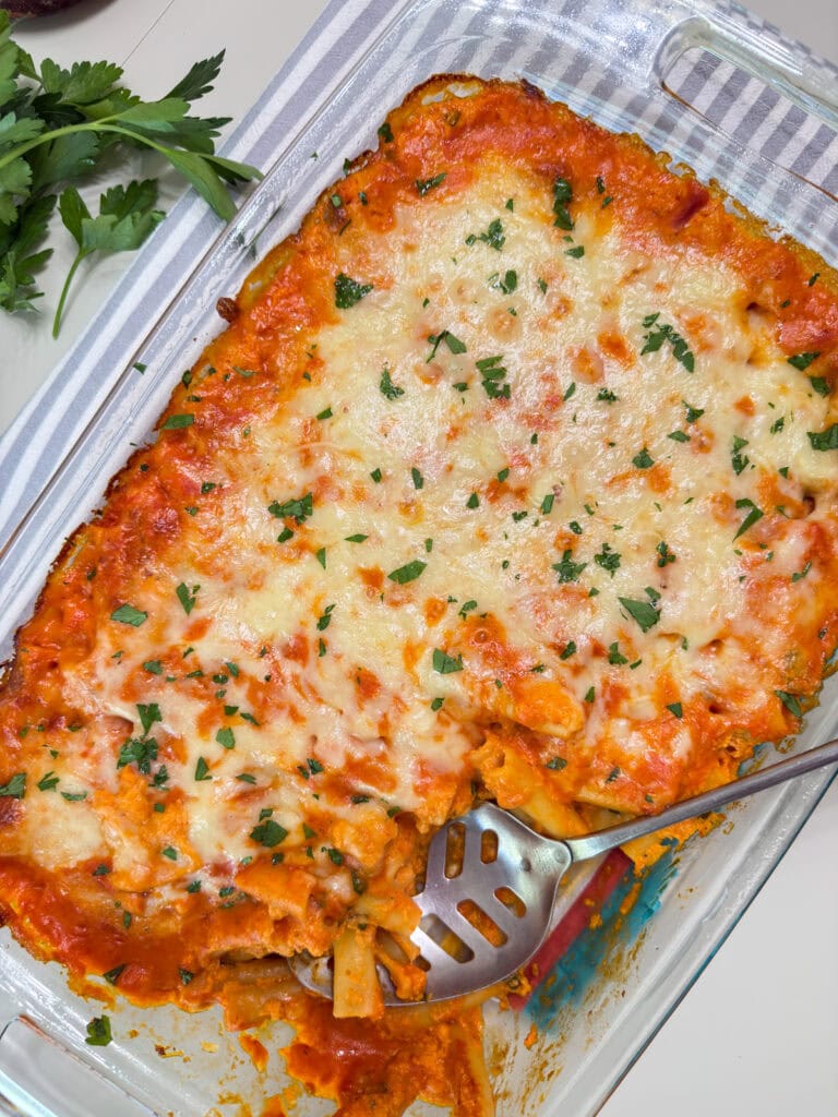 The baking dish with the baked ziti in it, with one serving missing.