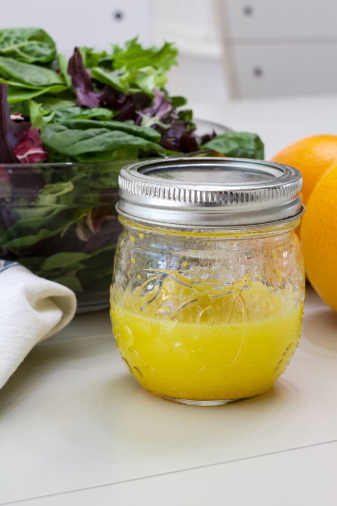 A small mason jar filled with the Orange Vinaigrette Salad Dressing Recipe.