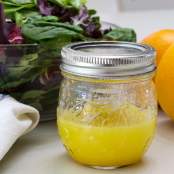 Close up straight on shot of the mason jar with the Orange Vinaigrette Salad Dressing in it.