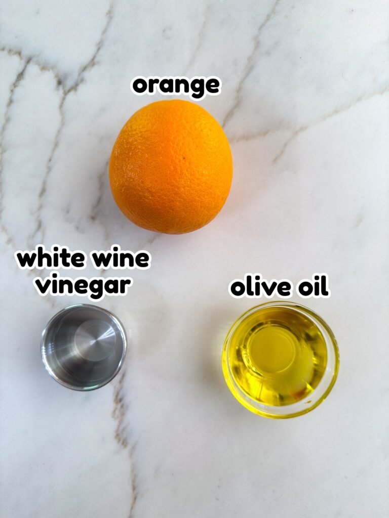 One orange and a small bowl of olive and a small bowl of vinegar needed to make the Orange Vinaigrette Salad Dressing Recipe.