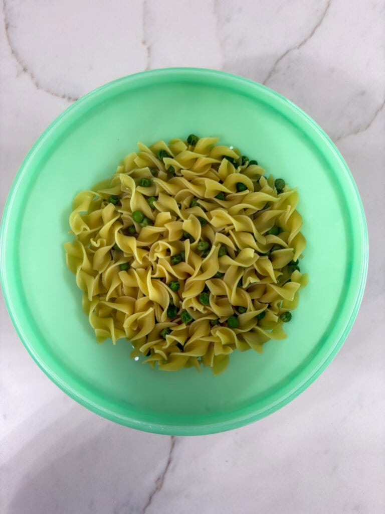 The cooked pasta and peas on a collander.