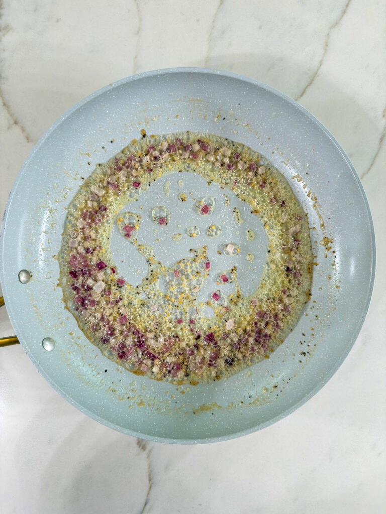 The melted butter, onion, garlic and black pepper in the skillet.
