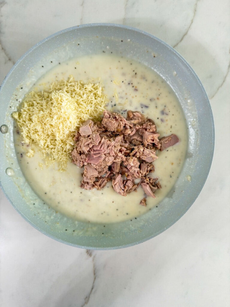 The skillet after the milk has been added and thickened then the parmesan cheese and canned tuna added.