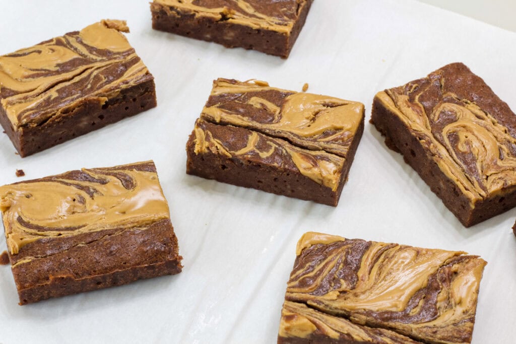Several cut brownies on a piece of white parchment paper.