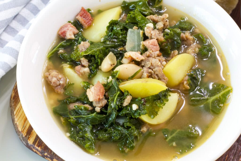 Overhead shot of one serving of Dairy Free Zuppa Toscana in a white bowl.