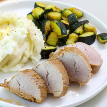 Feature image of tone serving of Easy Marinated Pork Tenderloin on a plate with potatoes and zucchini.