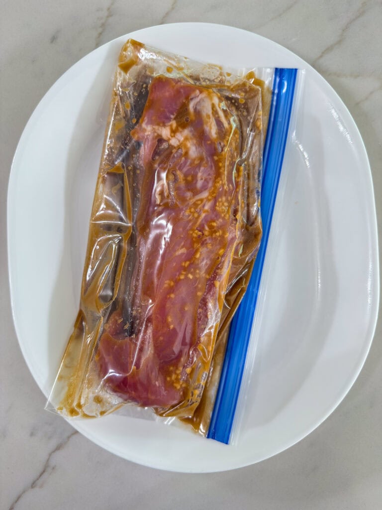 The pork tenderloin and marinade in a zip top bag on a plate ready to go into the fridge for 30 minutes.