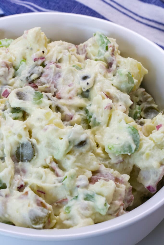 Close up side shot of the Healthy Potato Salad (no eggs) in a white serving bowl.