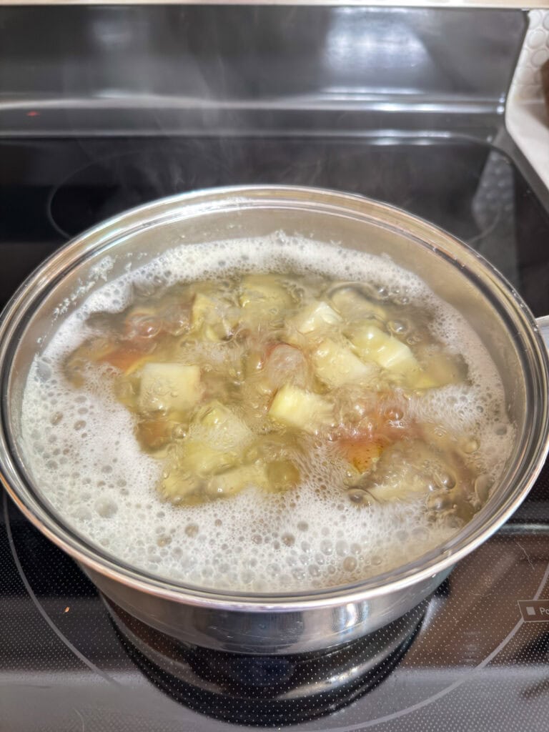 A pot of boiling potatoes on the top of the stove.