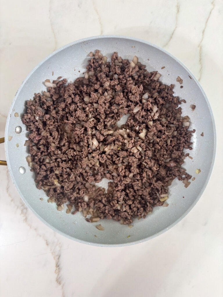 The browned beef and onion in the skillet.