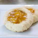 Close up on one cookie leaning on another cookie so the filling and glaze are visible.