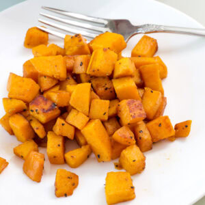 Feature image of one serving of cooked sweet potatoes on a white plate.