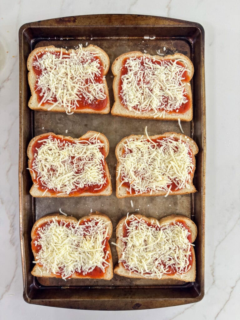 Six slices of sourdough bread topped with sauce and then cheese.