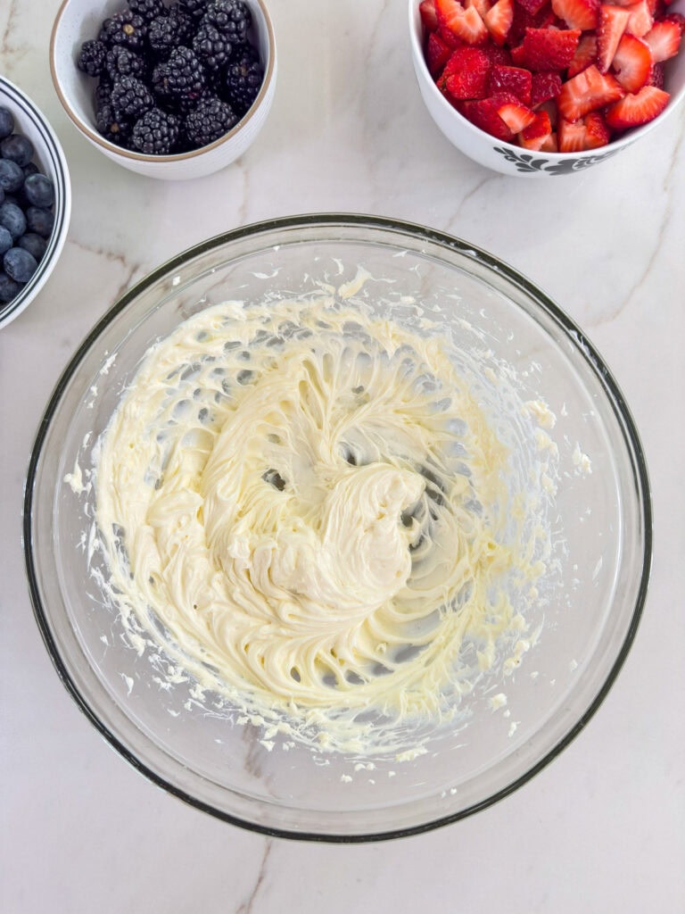The cream cheese and sugar mixed together in a large glass bowl.