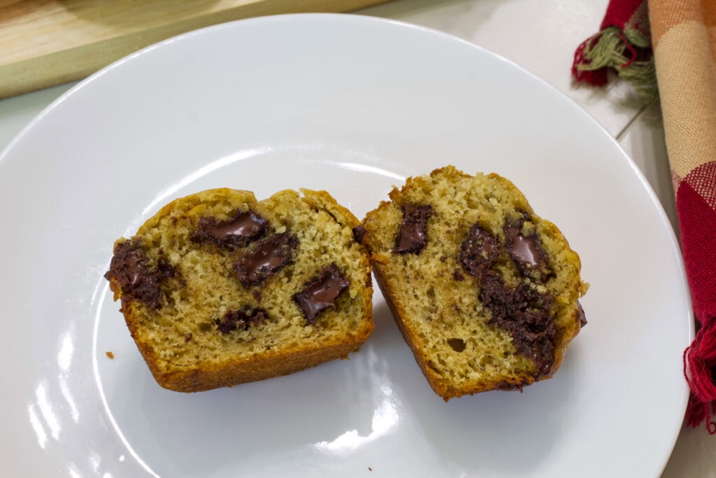 One Banana Chocolate Chunk Muffins cut open so the melty chocolate chunks on the inside are visible.
