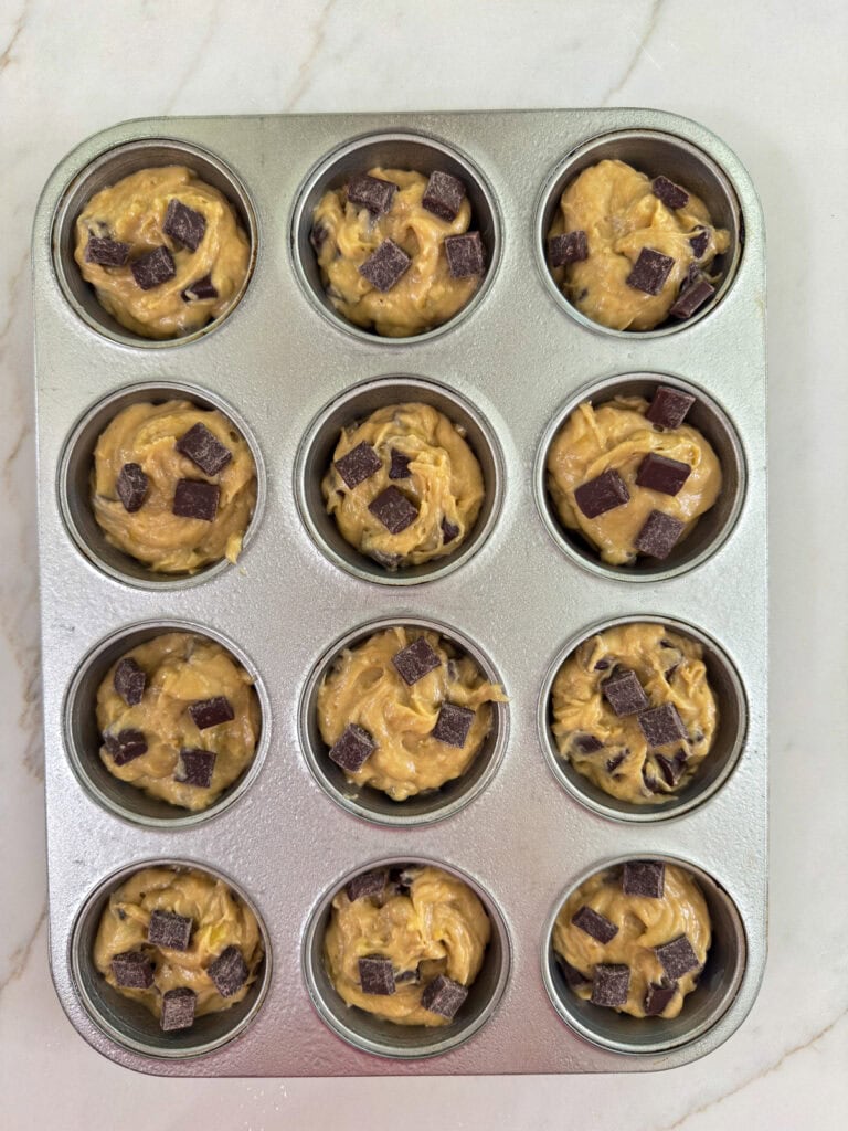 The muffin batter divided between 12 muffin cups ready to go into the oven.