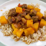 Feature image of a close up of a serving of tagine on a white plate.