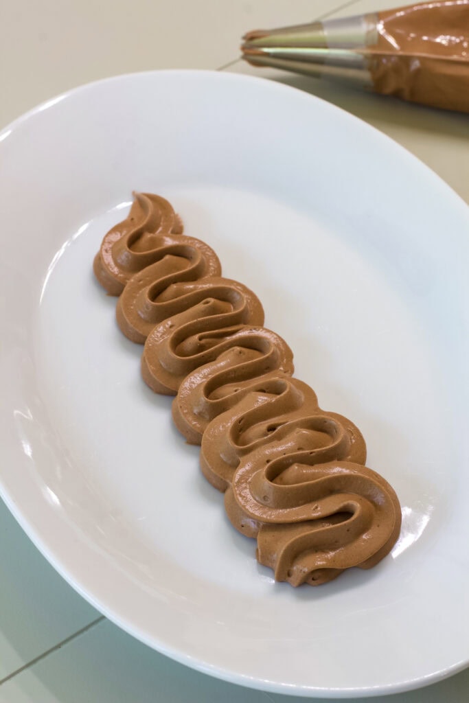 Some Chocolate Pudding Cool Whip Frosting piped onto a white plate.