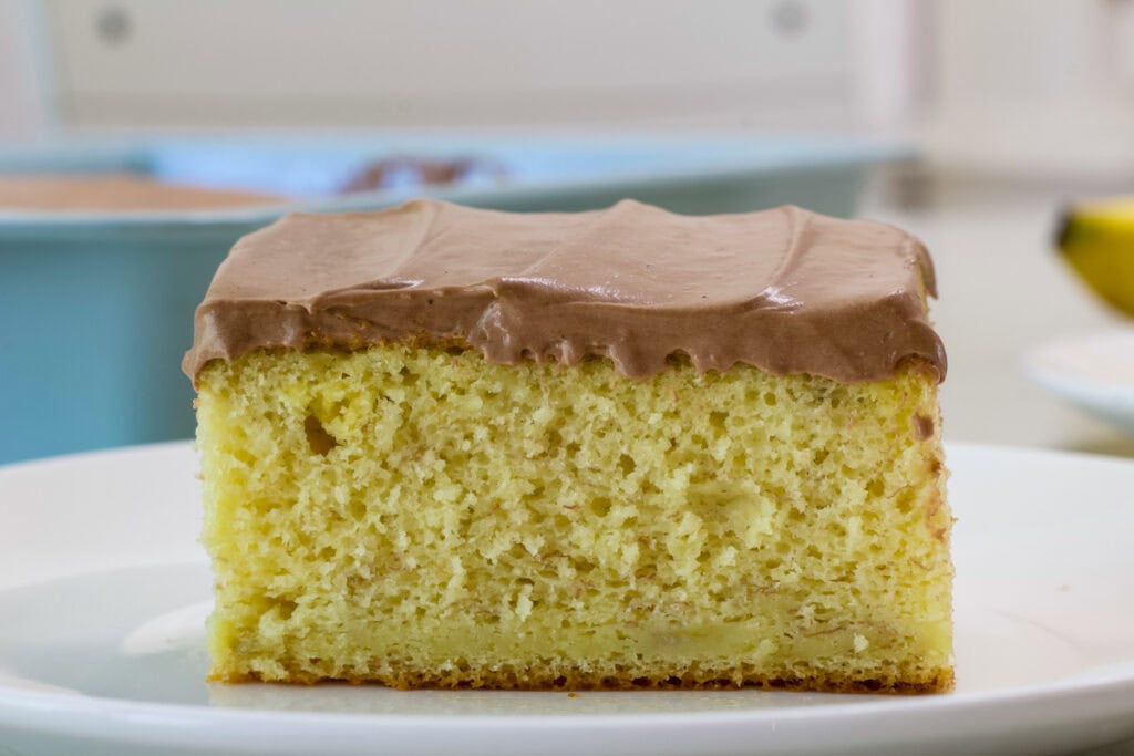 A piece of banana cake topped with Chocolate Pudding Cool Whip Frosting.